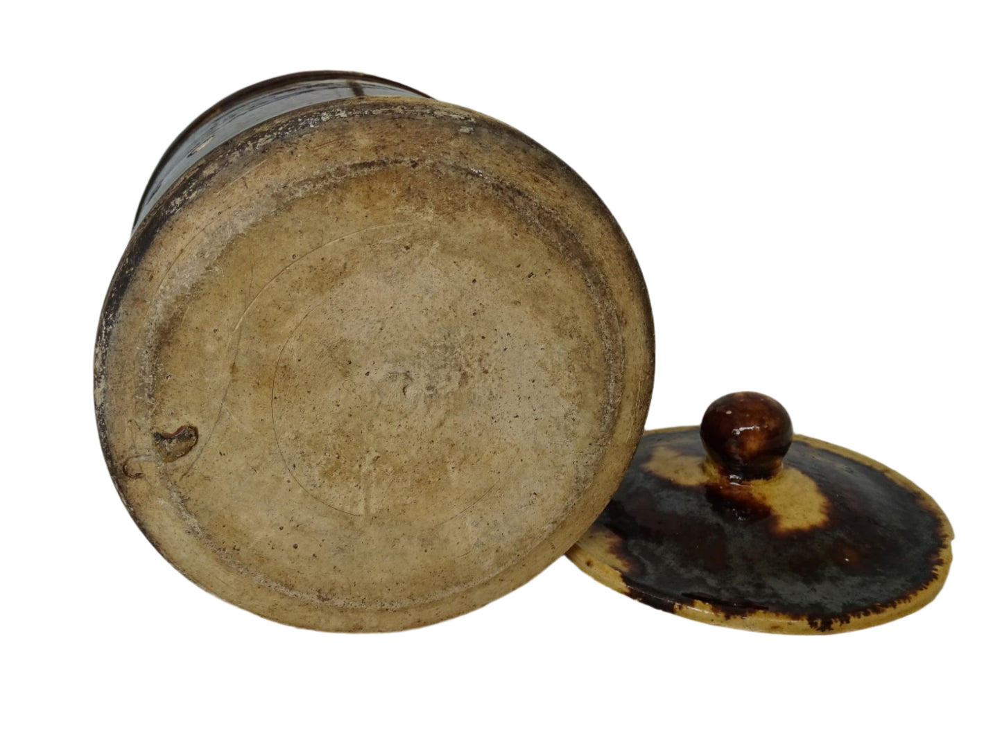 French antique pottery pitcher with a lid. Old ceramic jug with a brown drip glaze on a yellow glazed background.