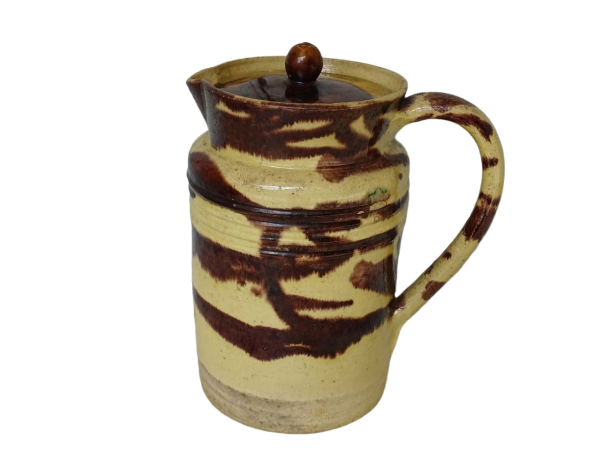 Large French antique ceramic pitcher with a lid. The glazed pottery jug has a gorgeous brown drip glaze on a yellow glazed background.