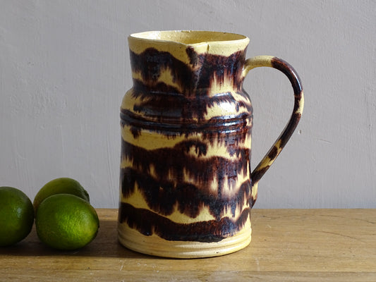 Rustic French antique ceramic pitcher with yellow glaze and brown drip glaze detailing. This Dieulefit pottery jug has a handle to the side.