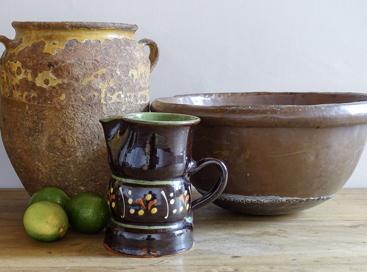 Beautifully rustic French vintage ceramic jug. It has a deep brown glaze and hand-painted decoration . This pottery jug is from Alsace. Pictured alongside a French antique copper bowl and a yellow confit pot.