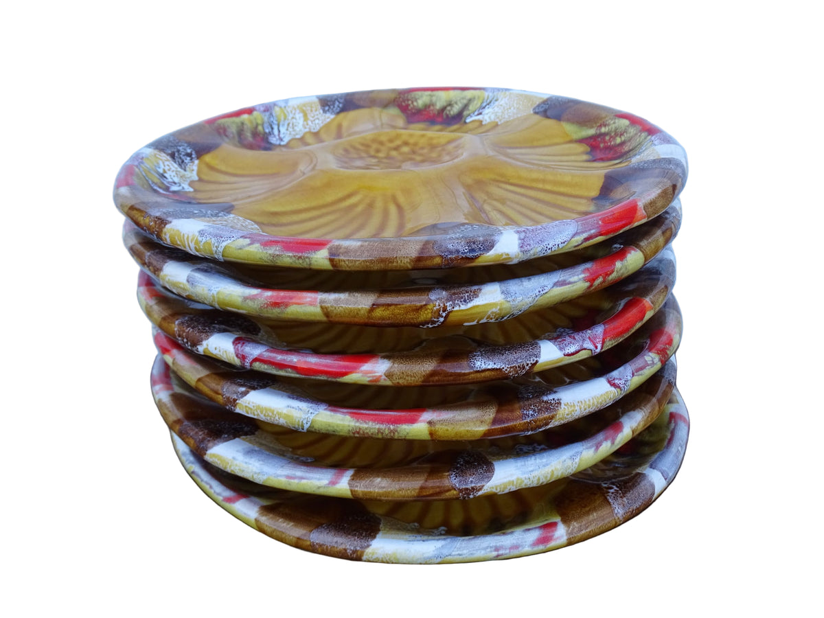 Stack of French vintage Vallauris pottery oyster plates with an ochre yellow glaze and a freeform edge in brown, red and white.