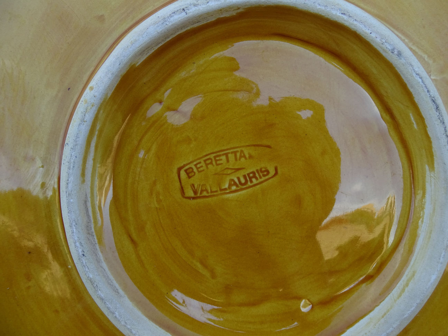 Close-up of a vintage yellow ceramic plate with 'Beretta Vallauris' branding.