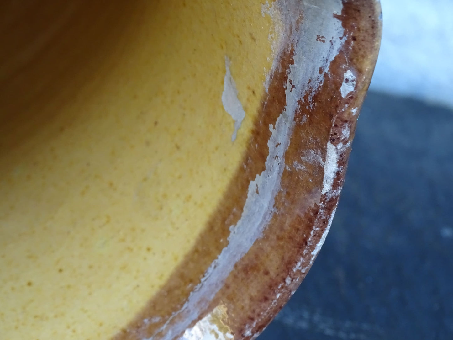 Brown French antique pottery pitcher with yellow glaze interior. Timeworn ceramic jug with handle and spout.