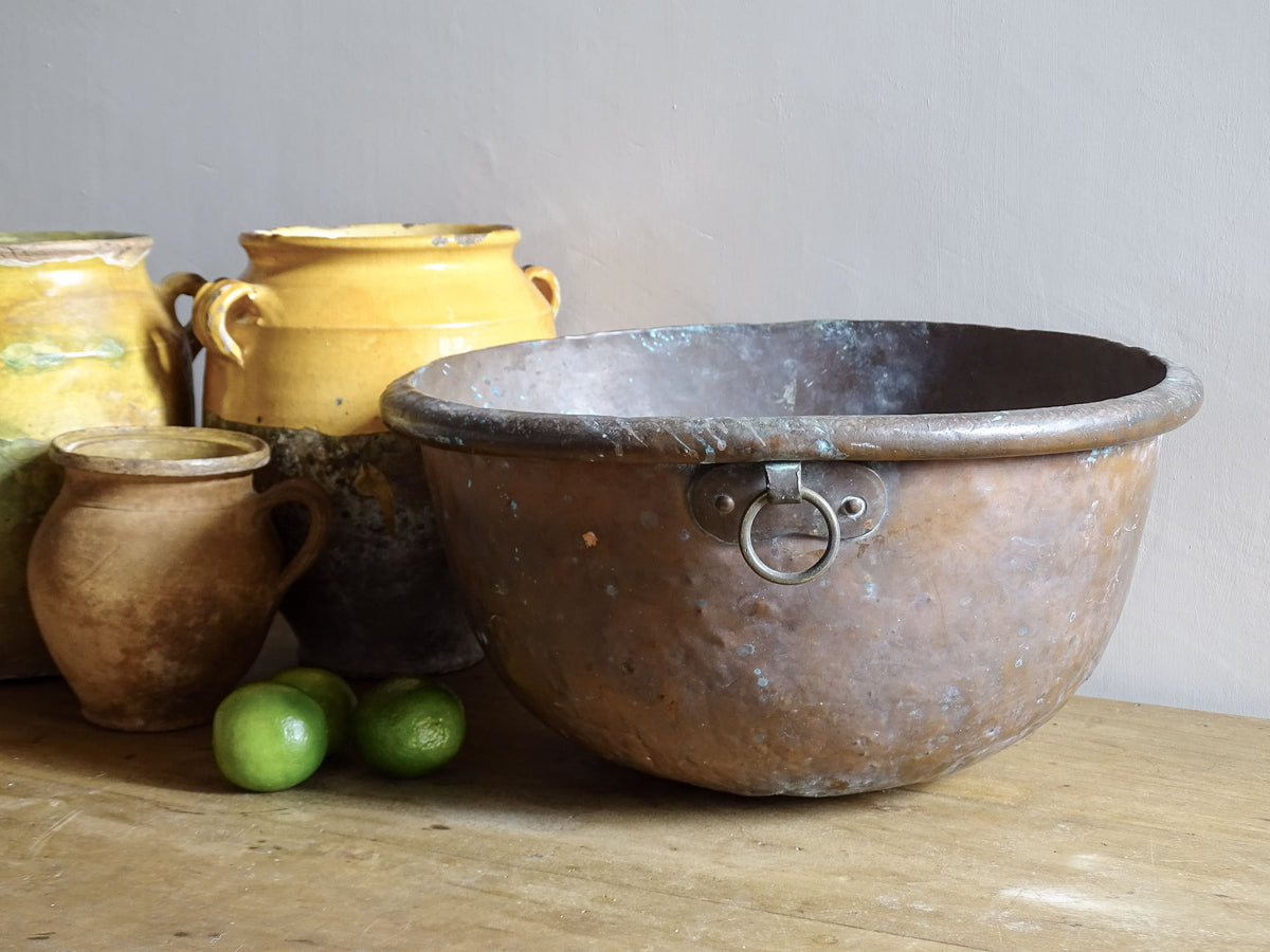 French antique copper bowl for confectioners, 18th Century. A copper confectioner's Bowl or meringue bowl for an antique farmhouse kitchen. The copper mixing bowl or cul de poule has a rich patina, rolled edge, curved base and a small loop handle. Pictured with yellow confit pots.