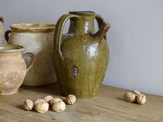 Antique French Terracotta Walnut Oil Jug with Green Glaze, pictured alongside french pottery and confit pots.