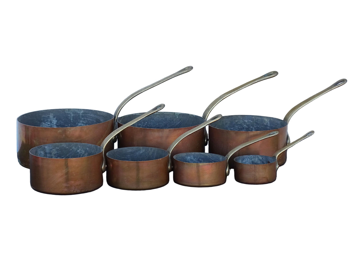 Set of seven French antique copper pans with brass handles. Tinned copper saucepans.