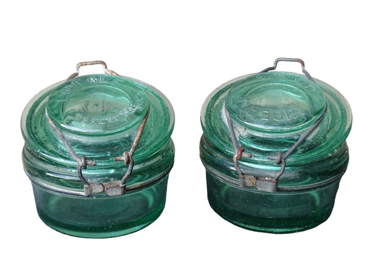 Pair of large French vintage green glass preserving jars by L'Ideale. They feature thick green glass, embossed detailing, and old metal clasps with a naturally aged finish.