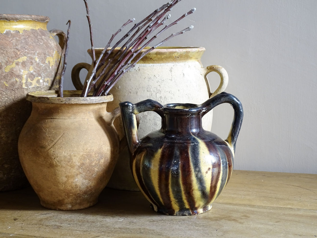 French antique ceramic jug or orjol with striped glaze. Glazed terracotta pitcher with yellow, black and brown glaze. Pictured alongside French antique pottery