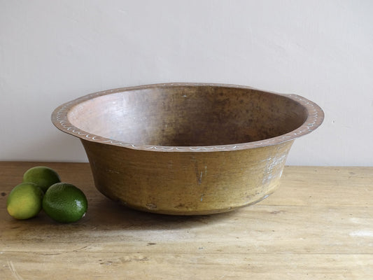 A timeworn French antique copper bowl with hammered detailing to the rim and a rounded base. This copper bowl has a beautiful, aged patina.