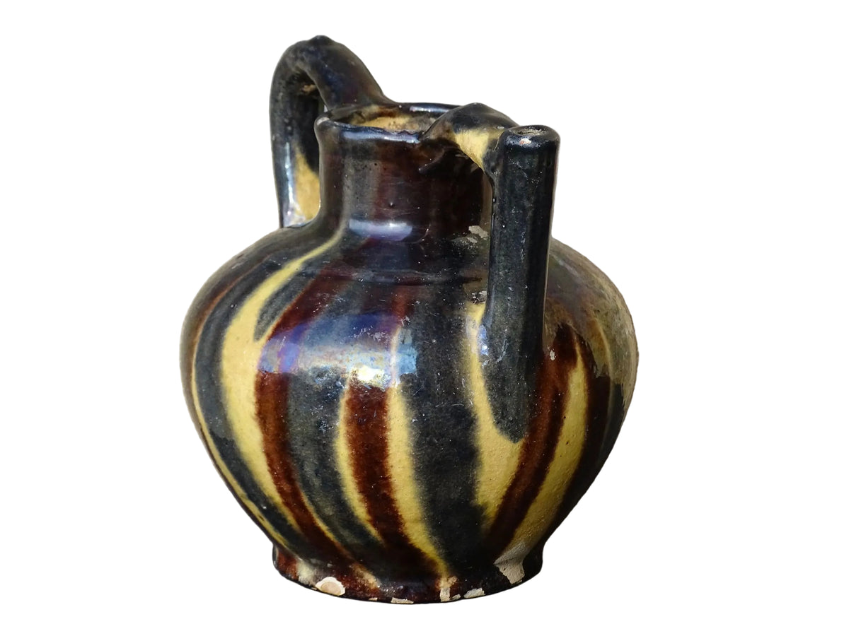 French antique ceramic jug or orjol with striped glaze. Glazed terracotta pitcher with yellow, black and brown glaze.