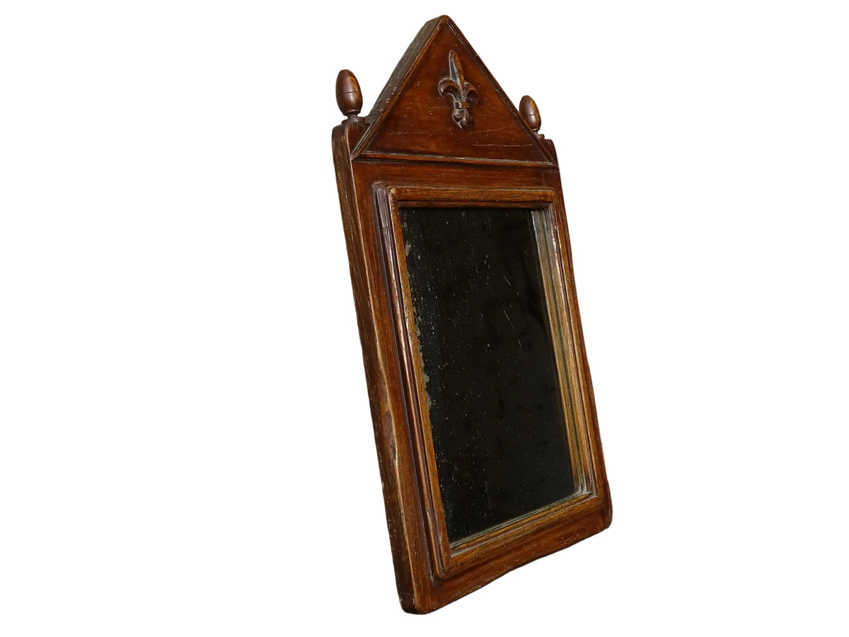 French antique wooden mirror with fleur de lis motif. The wood mirror is topped by a pediment with two turned finials.