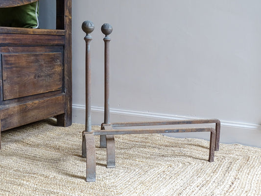 Pair of French antique cast iron andirons or fire dogs, dating to the 19th century. They are rustically aged. These antique fire dogs have globe finials and have beautifully simple farmhouse aesthetic.