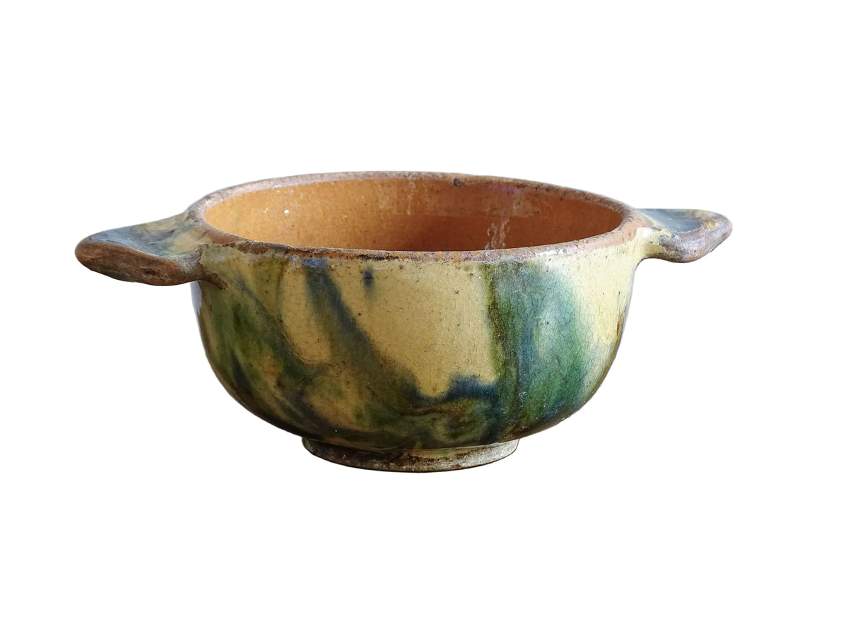A French vintage ceramic souvenir bowl from Vichy, in the Auvergne region of France. Decorated with hand-applied sponged slip in yellow, green and blue tones. Mid 20th century, with a warm rustic glaze and visible age-related crazing.
