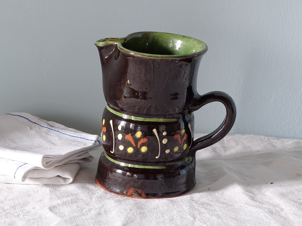 French vintage pottery jug with brown glaze and hand-painted decoration, pictured with antique linen