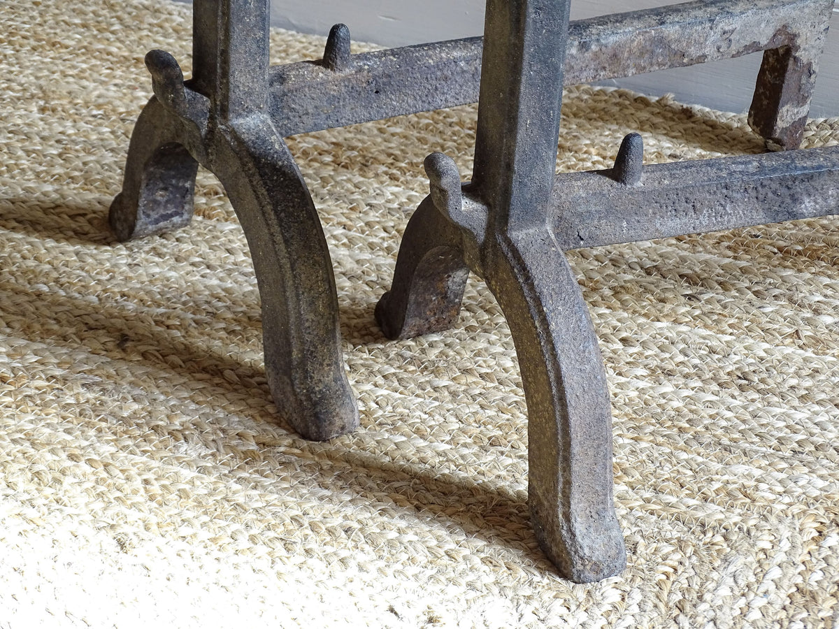 A pair of French antique cast iron andirons or fire dogs, date to the 19th century. They are large and heavy and each have two spit hooks to the front and bowls to the top.