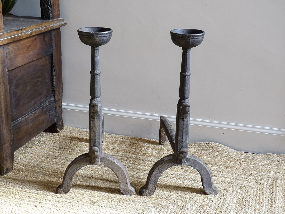A pair of French antique cast iron andirons or fire dogs, date to the 19th century. They are large and heavy and each have two spit hooks to the front and bowls to the top.