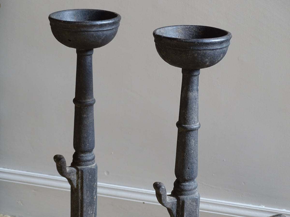 A pair of French antique cast iron andirons or fire dogs, date to the 19th century. They are large and heavy and each have two spit hooks to the front and bowls to the top.