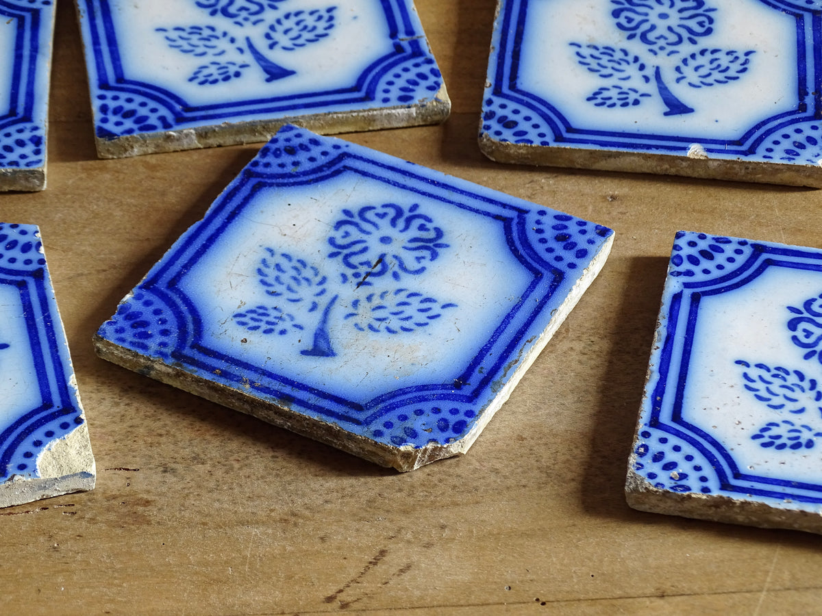 A set of eight French antique Desvres faience tiles in blue & white. These transfer printed, earthenware tiles were manufactured in the late 1900's in Desvres, Northern France. Six of the tiles are back-stamped. They are beautifully transfer printed in cobalt blue. A floral sprig sits in the centre of the cartouche framing.