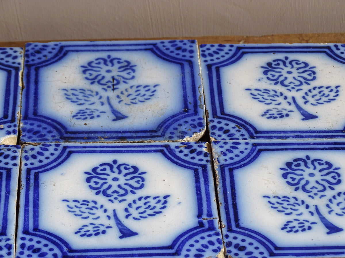 A set of eight French antique Desvres faience tiles in blue & white. These transfer printed, earthenware tiles were manufactured in the late 1900's in Desvres, Northern France. Six of the tiles are back-stamped. They are beautifully transfer printed in cobalt blue. A floral sprig sits in the centre of the cartouche framing.
