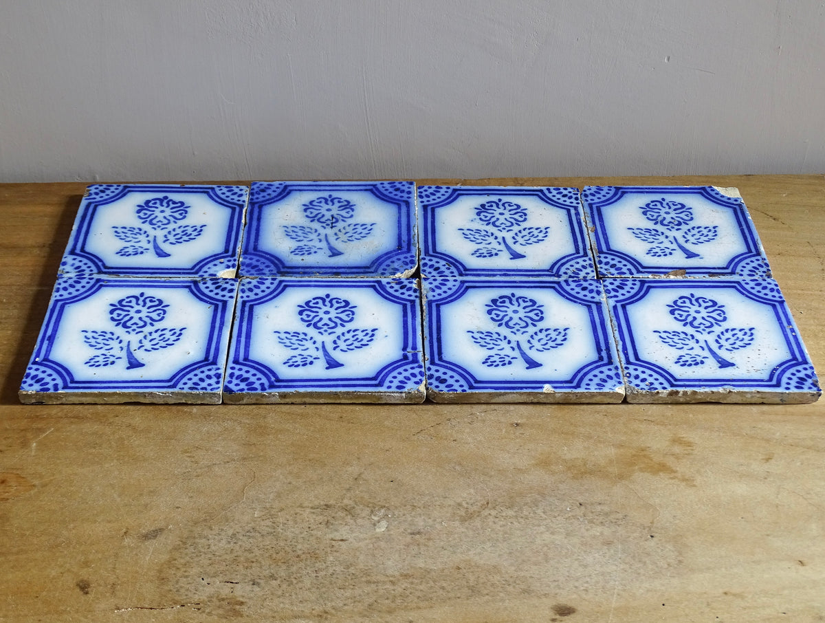A set of eight French antique Desvres faience tiles in blue & white. These transfer printed, earthenware tiles were manufactured in the late 1900's in Desvres, Northern France. Six of the tiles are back-stamped. They are beautifully transfer printed in cobalt blue. A floral sprig sits in the centre of the cartouche framing.