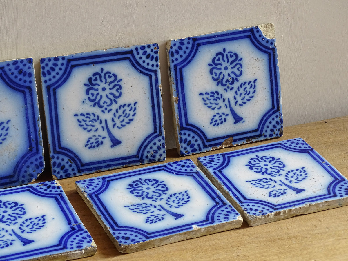 A set of eight French antique Desvres faience tiles in blue & white. These transfer printed, earthenware tiles were manufactured in the late 1900's in Desvres, Northern France. Six of the tiles are back-stamped. They are beautifully transfer printed in cobalt blue. A floral sprig sits in the centre of the cartouche framing.