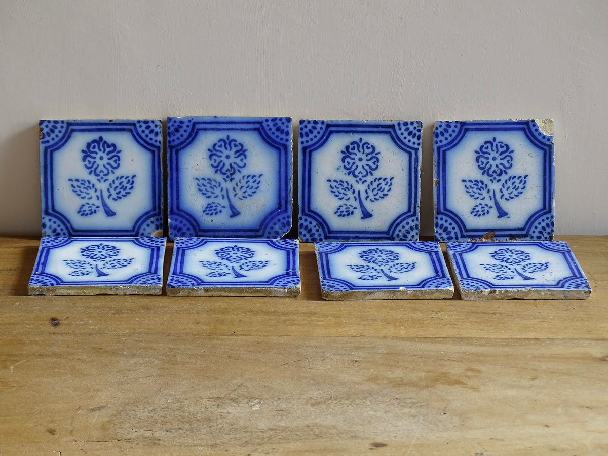 A set of eight French antique Desvres faience tiles in blue & white. These transfer printed, earthenware tiles were manufactured in the late 1900's in Desvres, Northern France. Six of the tiles are back-stamped. They are beautifully transfer printed in cobalt blue. A floral sprig sits in the centre of the cartouche framing.