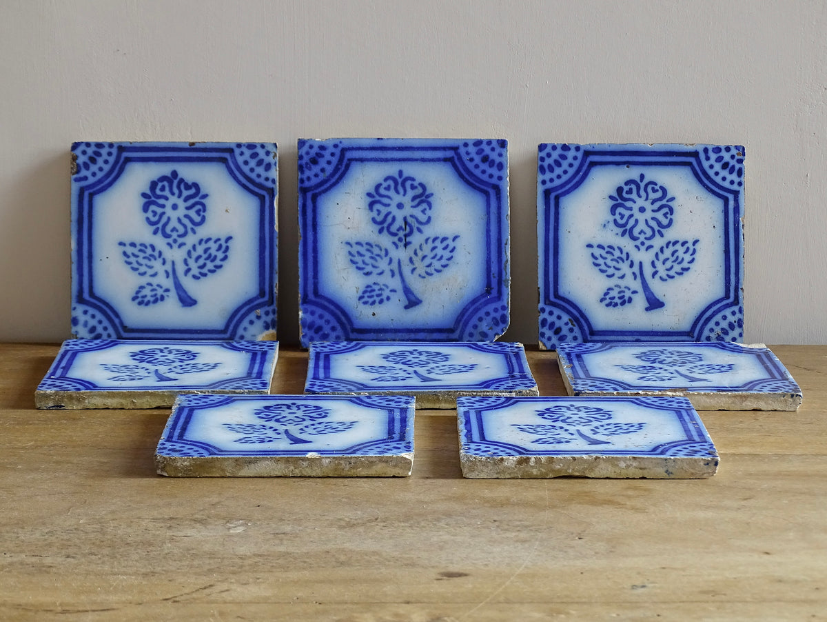 A set of eight French antique Desvres faience tiles in blue & white. These transfer printed, earthenware tiles were manufactured in the late 1900's in Desvres, Northern France. Six of the tiles are back-stamped. They are beautifully transfer printed in cobalt blue. A floral sprig sits in the centre of the cartouche framing.