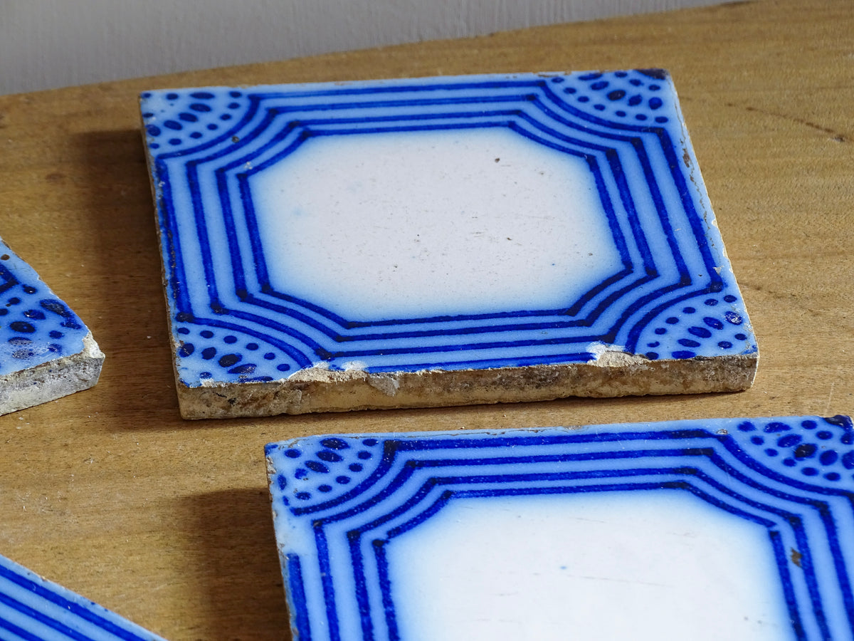 A set of six French antique Desvres faience tiles in blue & white. These transfer printed, earthenware tiles were manufactured in the late 1900's in Desvres, Northern France. Five of the tiles are back-stamped. They are beautiful, transfer printed, architectural blue and white faience tiles with layered cobalt blue cartouche framing.