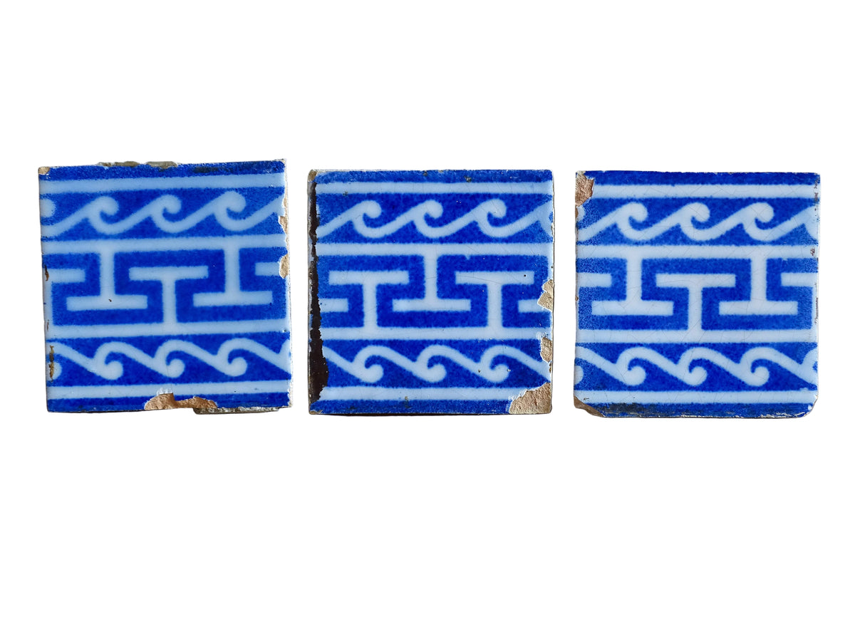 A set of three French antique Desvres faience tiles in blue & white. These transfer printed, earthenware tiles were manufactured in the late 1900's in Desvres, Northern France. These antique tiles are back-stamped with the maker's mark. They are beautifully transfer printed in cobalt blue with a repeating Greek key motif and stylised wave border.