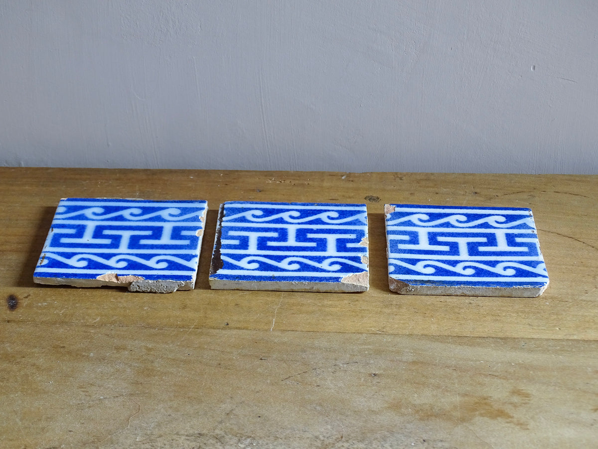 A set of three French antique Desvres faience tiles in blue & white. These transfer printed, earthenware tiles were manufactured in the late 1900's in Desvres, Northern France. These antique tiles are back-stamped with the maker's mark. They are beautifully transfer printed in cobalt blue with a repeating Greek key motif and stylised wave border.