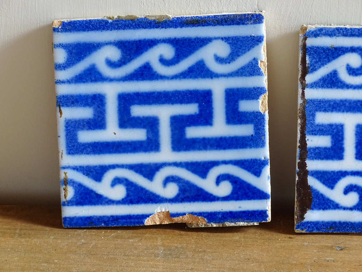 A set of three French antique Desvres faience tiles in blue & white. These transfer printed, earthenware tiles were manufactured in the late 1900's in Desvres, Northern France. These antique tiles are back-stamped with the maker's mark. They are beautifully transfer printed in cobalt blue with a repeating Greek key motif and stylised wave border.