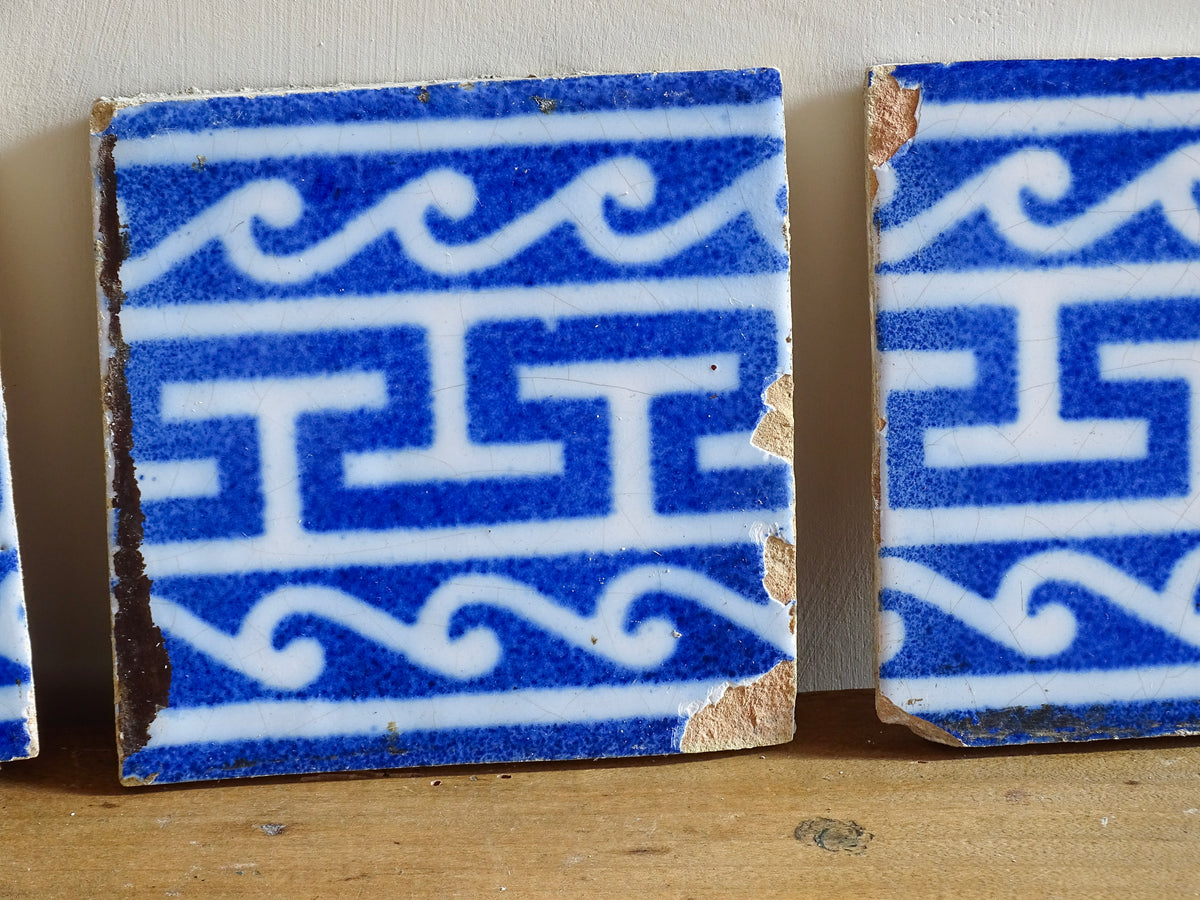 A set of three French antique Desvres faience tiles in blue & white. These transfer printed, earthenware tiles were manufactured in the late 1900's in Desvres, Northern France. These antique tiles are back-stamped with the maker's mark. They are beautifully transfer printed in cobalt blue with a repeating Greek key motif and stylised wave border.