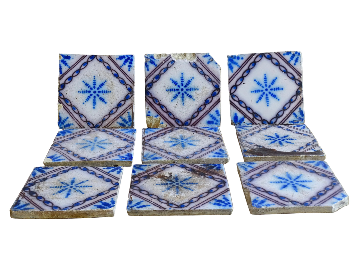 A set of nine French antique Desvres faience tiles in blue & white. These transfer printed, earthenware tiles were manufactured in the late 1900's in Desvres, Northern France. The tiles are back-stamped. Each tile is decorated in cobalt blue on a white tin-glazed ground, centred with a stylised starburst motif and framed within a manganese-purple diamond border.