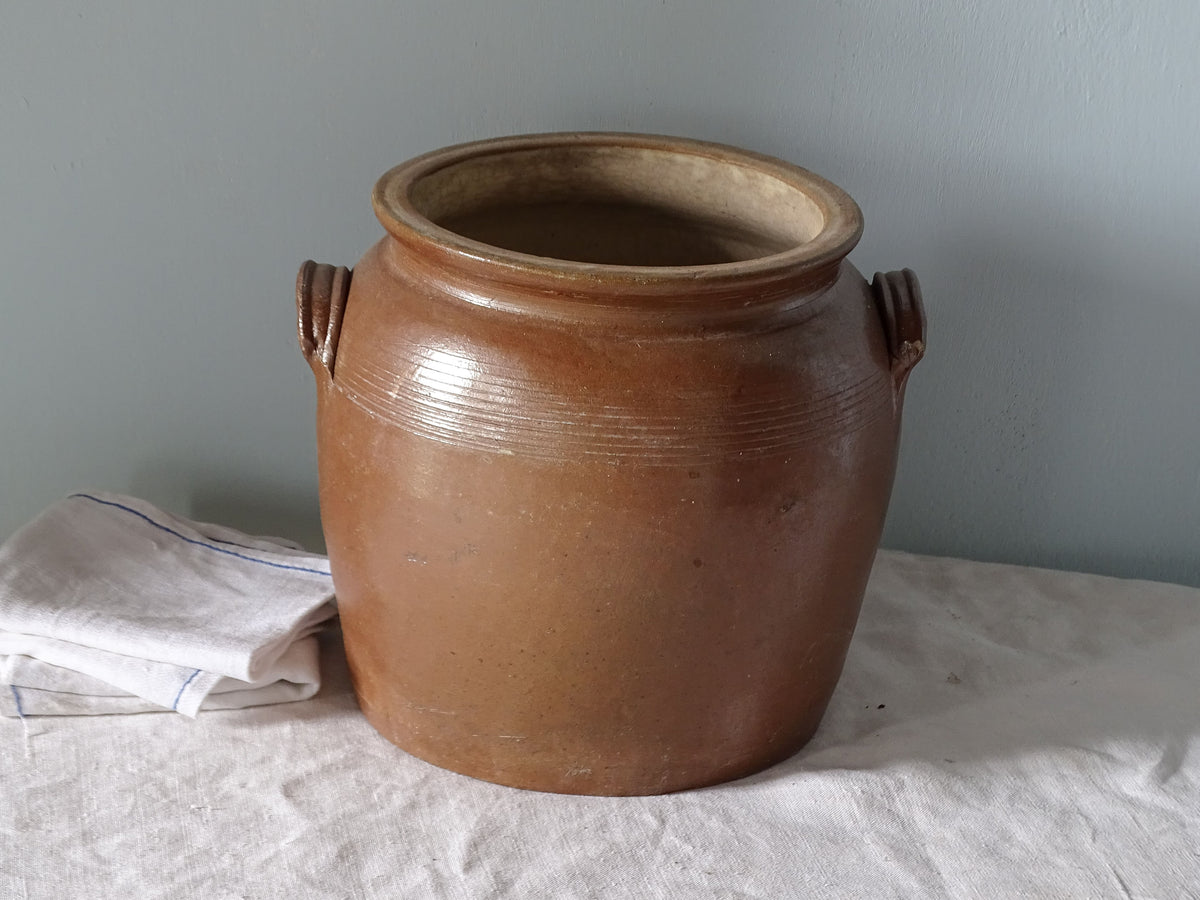 French antique stoneware pot with brown glaze, pictured with antique linen