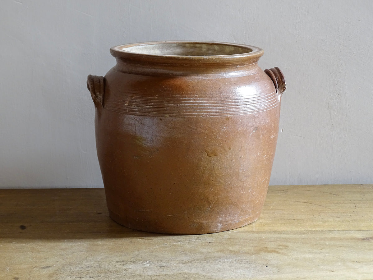 A French antique stoneware confit pot with a brown glaze. This is a salt glazed pottery cache pot. It dates to the early 20th century and would look amazing as part of a rustic French farmhouse style home.