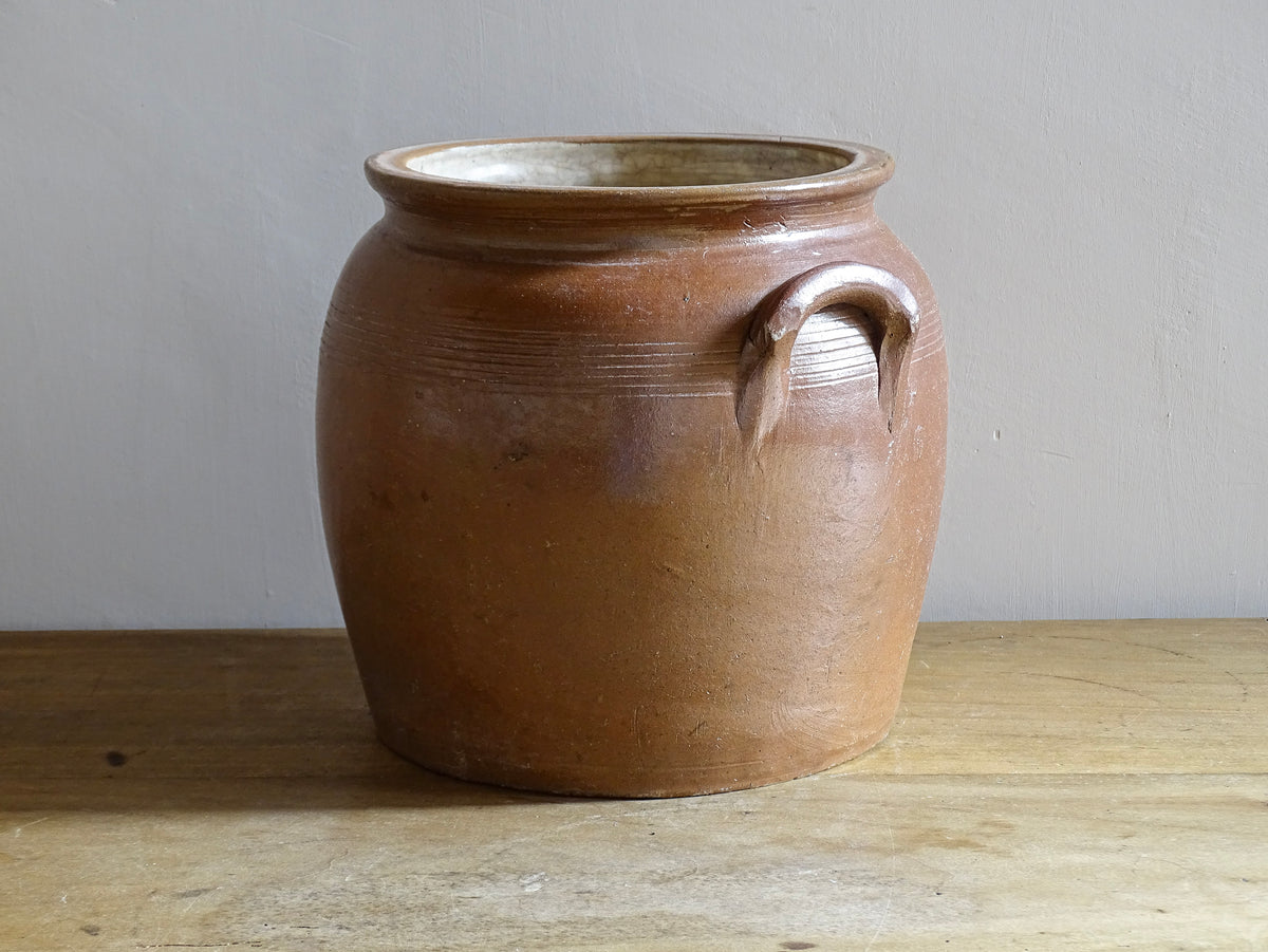 A French antique stoneware confit pot with a brown glaze. This is a salt glazed pottery cache pot. It dates to the early 20th century and would look amazing as part of a rustic French farmhouse style home.