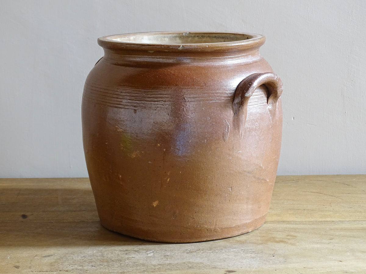 A French antique stoneware confit pot with a brown glaze. This is a salt glazed pottery cache pot. It dates to the early 20th century and would look amazing as part of a rustic French farmhouse style home.