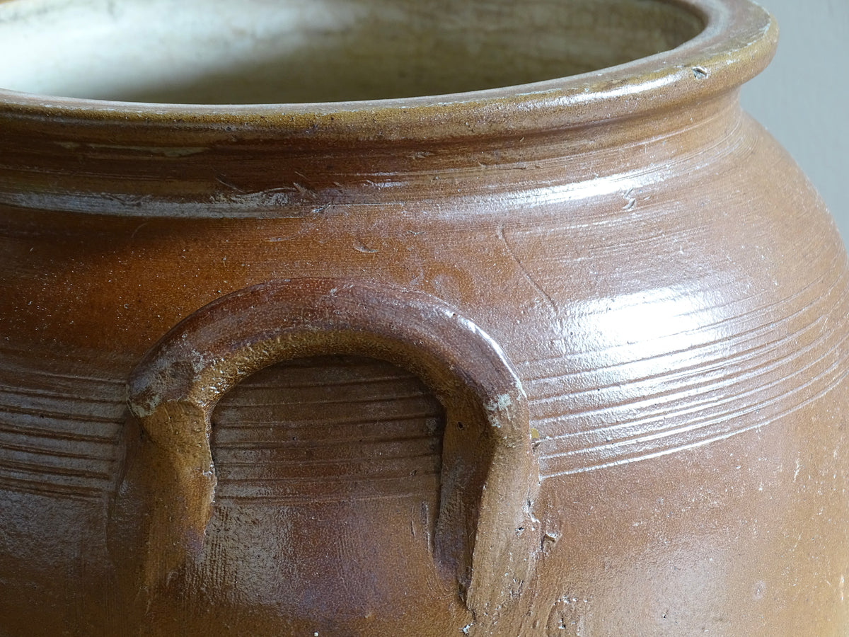 A French antique stoneware confit pot with a brown glaze. This is a salt glazed pottery cache pot. It dates to the early 20th century and would look amazing as part of a rustic French farmhouse style home.