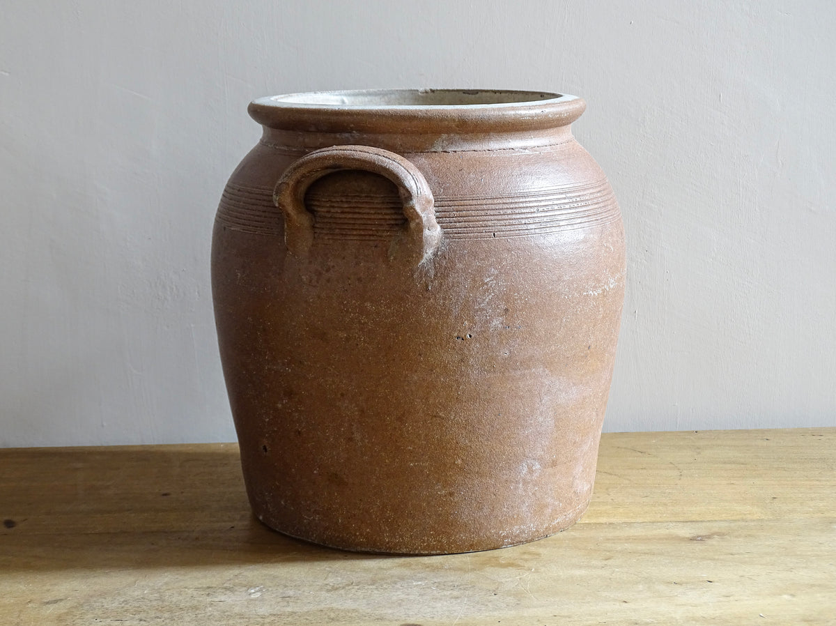 A French antique stoneware confit pot with a brown glaze. This is a salt glazed pottery cache pot. It dates to the early 20th century and would look amazing as part of a rustic French farmhouse style home.