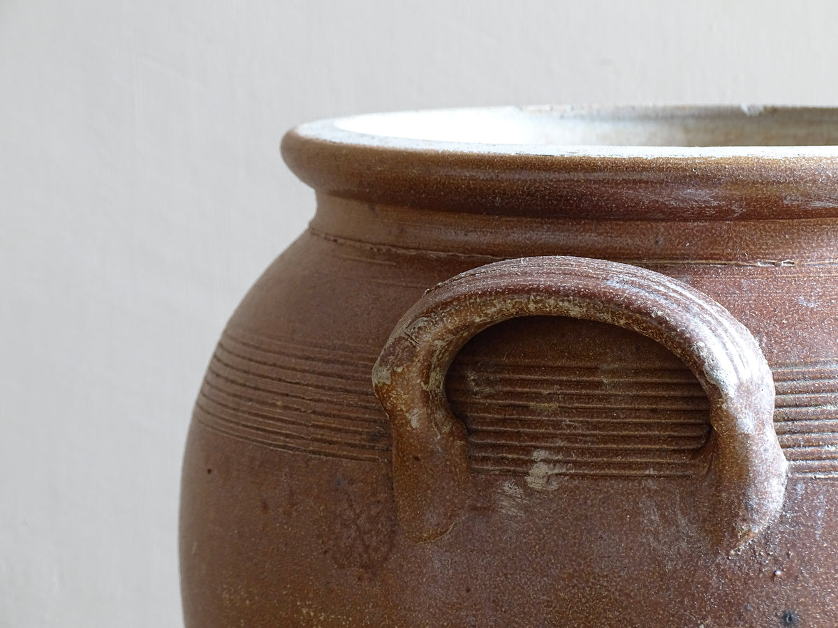 A French antique stoneware confit pot with a brown glaze. This is a salt glazed pottery cache pot. It dates to the early 20th century and would look amazing as part of a rustic French farmhouse style home.