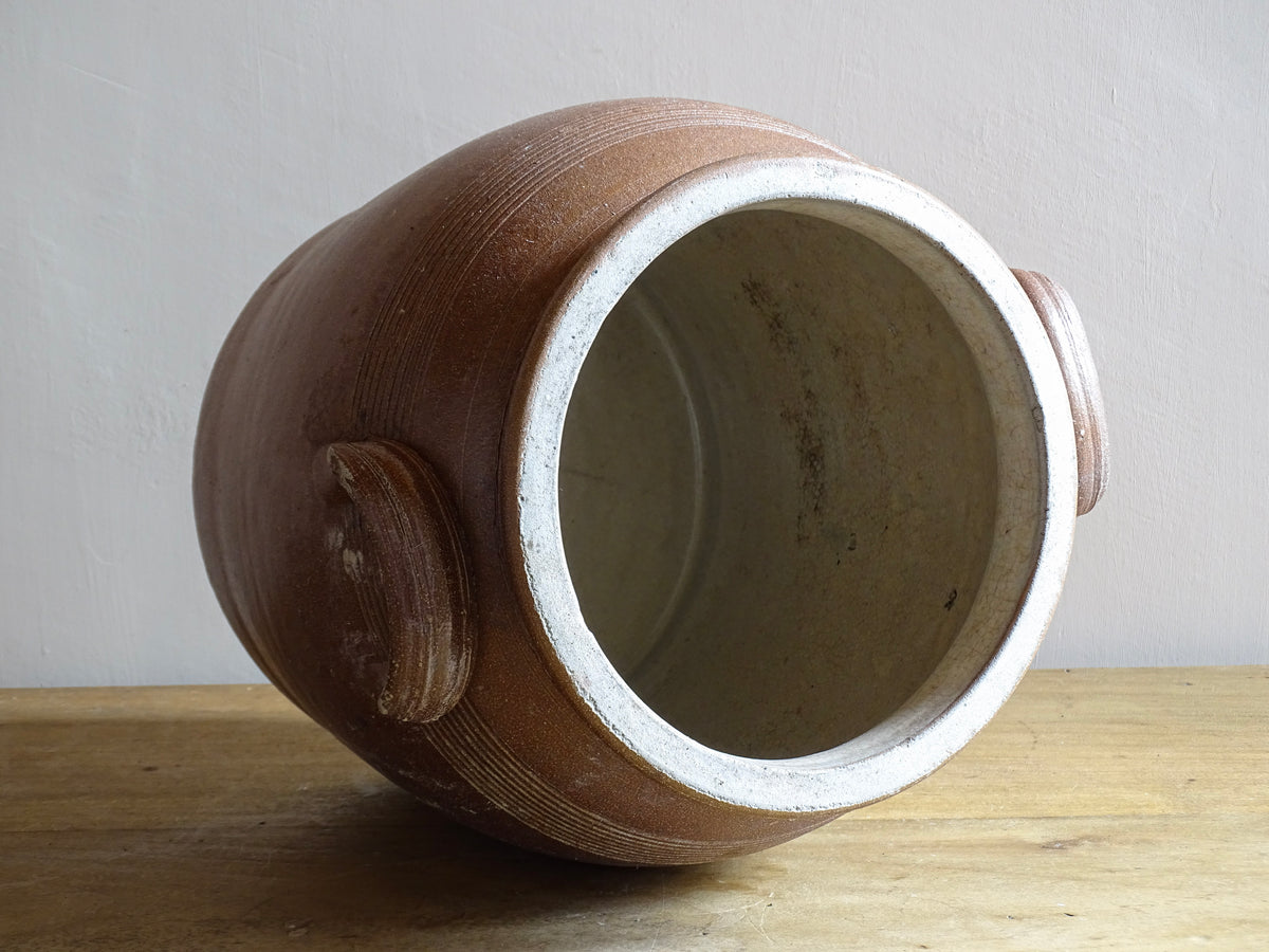 A French antique stoneware confit pot with a brown glaze. This is a salt glazed pottery cache pot. It dates to the early 20th century and would look amazing as part of a rustic French farmhouse style home.