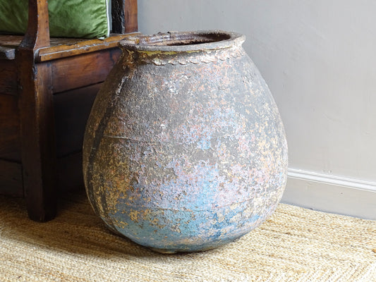 A large, early 19th century French antique terracotta pot, known as a ponne (salting pot), sourced in the Bordeaux region and likely Charentais in origin. This example has a beautifully rounded, generous form with a rolled rim. The surface is particularly special, showing layers of time, wear and historic pigment. Traces of faded blue and earthy tones remain across the body, creating a richly textured patina.