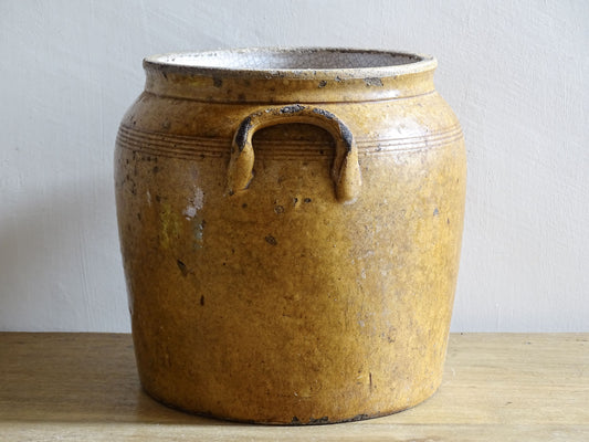 French antique stoneware pot with patina. A pottery confit pot with two handles and a brown glaze.