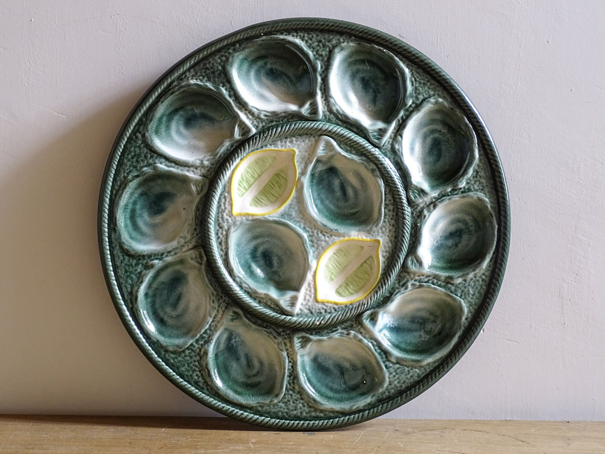 Vintage St Clément oyster plate from France showing twelve oyster shells and central well for lemon or sauce.