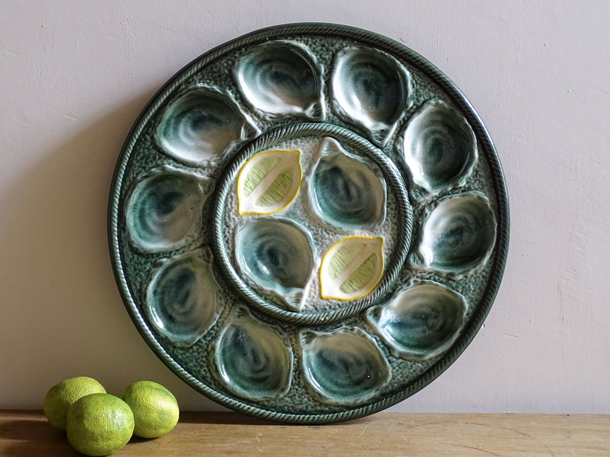 Vintage French oyster plate by St Clément with green glaze and twelve oyster wells surrounding a central sauce well.