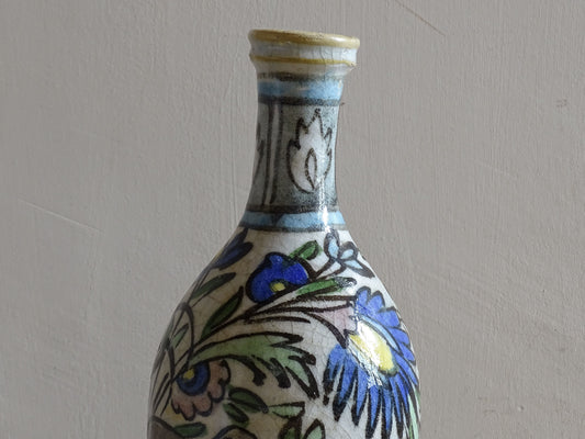 Decorative antique pottery bottle with deer and rabbit in floral landscape.