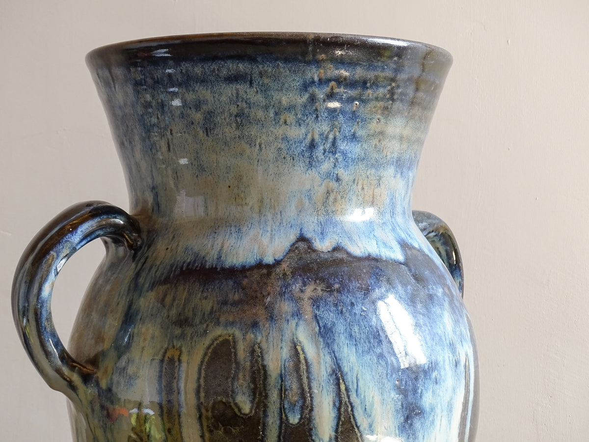 A large vintage studio pottery vase with a blue drip glaze. This stunning ceramic vase has a sculptural amphora form and twin handles, finished in a layered blue drip glaze.