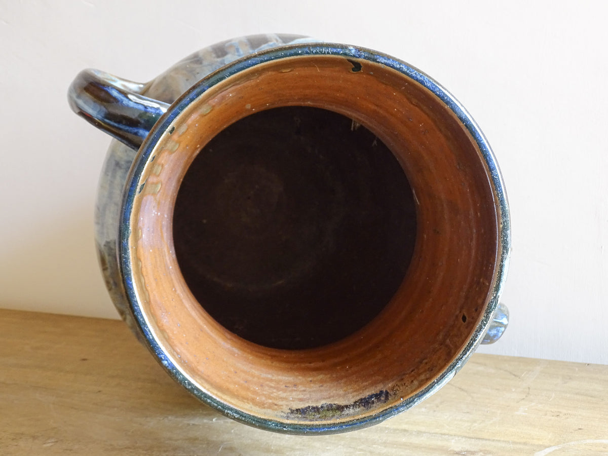 A large vintage studio pottery vase with a blue drip glaze. This stunning ceramic vase has a sculptural amphora form and twin handles, finished in a layered blue drip glaze.