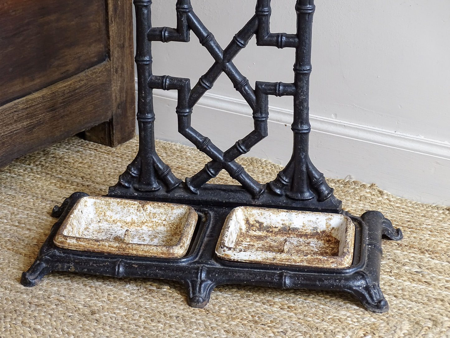 A striking French antique umbrella stand in cast iron, featuring an intricate bamboo-form design with geometric lattice detailing and original drip trays. Dating to the late 19th century