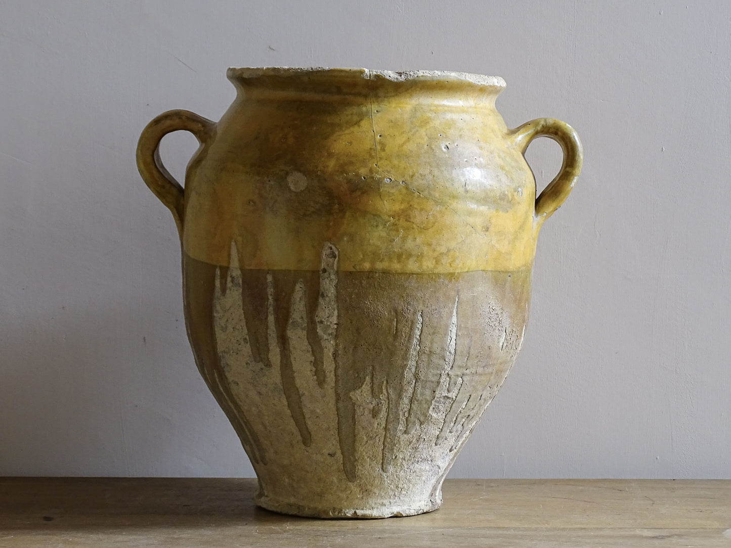 A large French antique confit pot in terracotta with two handles. Dating to the late 19th century and finished with a warm yellow glaze across the upper half.